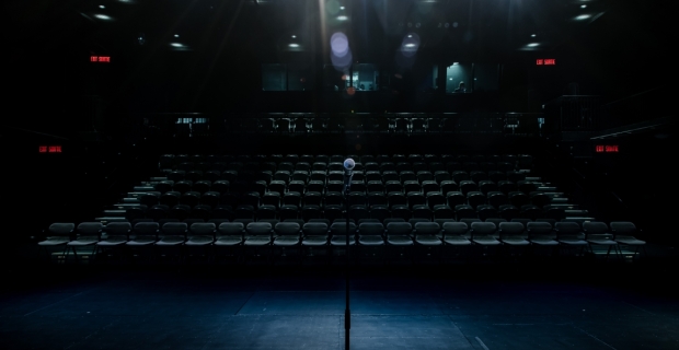 Theatric lights shining on a mic stand on a stage.