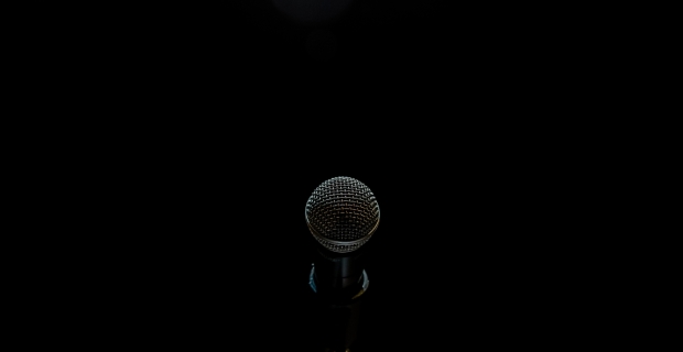 Theatric lights shining on a mic stand on a stage.