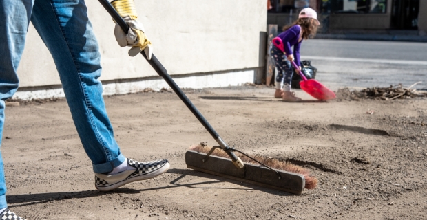 A grown up and child sweeping up debris