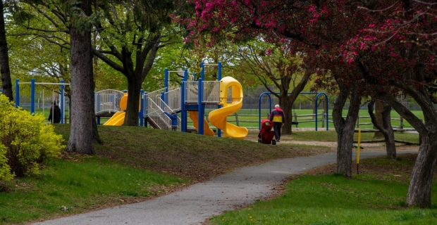 A walkway leading to a play structure in a wooden area at Craig Henry Park