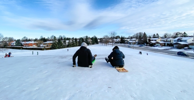 Two sledders at the top of the tobogganing hill in Neil-Nesbitt Park