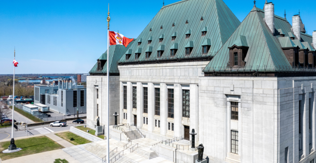 Front exterior view of the Supreme Court of Canada Building. One can see the Court flag flying in the breeze. 