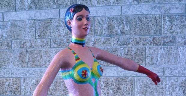 A painted plywood sculpture of a woman's torso and legs.