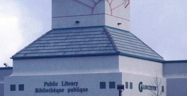 Image shows the red steel sculpture atop the library depicting the sun, a chair, and other objects along with the French word "decouvrir" meaning "discover".