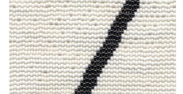 Photograph of a beaded canvas depicting a black scar or slash on a white background.