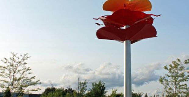 Sculpture mounted on pole with white, yellow, orange, and red petals.