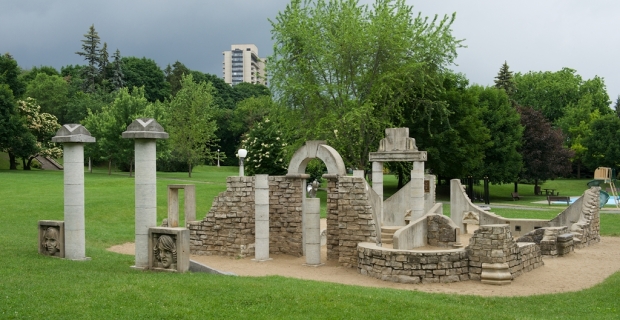 An archway, pillars and stone walls are arranged in a manner representing an ancient ruin.