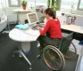 Handicapped woman in wheelchair in an office working on a computer.