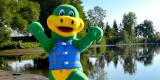 a green and yellow smiling dinosaur mascot wearing a blue life vest.