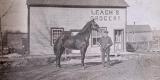 A man and a horse standing outside Leach's Store in North Gower