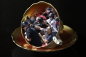 red and gold tea cup with image of protesters inside