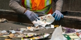 An employee stands behind a conveyor belt sorting paper products for recycling.  