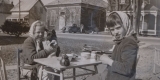 Deux enfants prennent le thé à l’extérieur d’une petite salle, probablement peu après la Seconde Guerre mondiale.