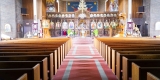 L’intérieur de l’église comporte des tapis rouges et des bancs en bois mène à une iconostase lumineuse.