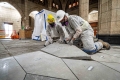 Travailleurs spécialisés enlevant soigneusement les dalles numérotées du sol en marbre à l'intérieur de l'édifice du Centre.