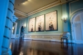 Couloir avec une série d'œuvres d'art en trois pièces sur le mur. L'œuvre représente une femme avec des oiseaux blancs flottant autour de sa tête.