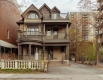 Une maison en briques brunes de trois étages avec un grand porche et des balcons un jour d’automne.