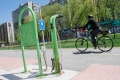 Un cycliste passe devant une station verte de réparation de vélos.