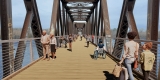 Rendering of pedestrians walking on the new multi-use pathway of the Chief William Commanda Bridge with a blue sky in the background and water beneath.