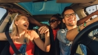 Intérieur d’une voiture avec deux femmes et un homme souriant et riant.