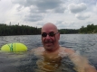 Marty, portant des lunettes de natation, nage dans un lac bordé d’arbres en toile de fond.