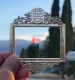 Un drapeau canadien flottant dans un paysage montagneux, encadré au premier plan par un cadre traditionnel chinois tenu par le photographe.