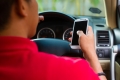 Rear view of a young man using his cell phone while driving/Photo prise derrière un jeune homme qui se sert de son téléphone cellulaire au volant