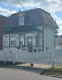 white and green heritage building with white picket fence in front