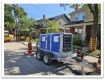 une grosse pompe sur une remoque, stationné devant une maison avec des cônes de construction.