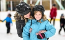 A girl and adult skating in an arena