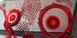 installation of bright red yarn in various crocheted shapes and patterns