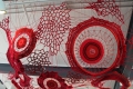 installation of bright red yarn in various crocheted shapes and patterns