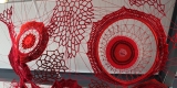 Installation faite de fil rouge représentant différentes formes et figures fabriquées au crochet