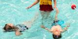 Photo de deux enfants apprenant à nager dans une piscine municipale.
