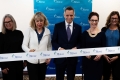 Mayor Mark Sutcliffe and event guests cut large white ribbon with Ottawa backdrop in behind.