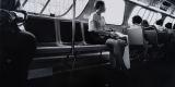 Photographie en noir et blanc d'une personne assise dans le bus
