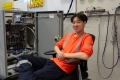 Co-op student, Ivan Feng, smiling and sitting in front of a traffic signal box that will be installed at an intersection.