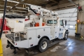 A white signals bucket truck parked inside a warehouse.
