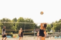 Men and women playing beach volleyball on a sunny day.