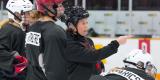 L’entraîneuse Carla MacLeod, équipée d’un casque noir, discute avec des joueurs sur la glace. Photo : LPHF d’Ottawa