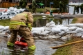 Un pompier installe une pompe à eau dans un fossé inondé.