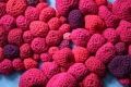 Vue rapprochée d’une installation composée de fils rouges crochetés et tricotés. 