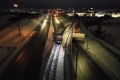 Aerial view of first train testing on the O-Train East Extension, Line 1, on the track at nighttime in winter with snow on the ground.