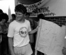 Terry Fox devant un mur de briques, tenant une banderole avec des signatures. On aperçoit la Tour de la Paix à l’arrière-plan.