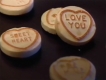 Video still of various light pink coloured heart candies with text on a black background