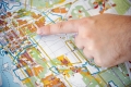 A close-up of a hand with a finger pointing to downtown Ottawa on a map with coloured blocks indicating zoning information. Gros plan d’une main dont un doigt montre le centre-ville d’Ottawa sur une carte dotée de formes colorées représentant l’information sur le zonage.