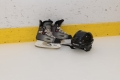 A pair of skates and helmet sitting near the boards on the ice.