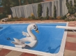 Cette peinture à l’huile représente une scène fantaisiste où un cygne gonflable flotte paisiblement sur l’eau, dans la piscine d’une cour arrière où la tranquillité règne, entourée d’une végétation abondante et d’une clôture en arrière-plan.