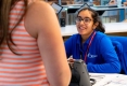 Trisha Bhatia sitting at a desk talking to a female customer.