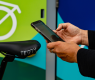 A close up on a pair of hands holding a phone, closing the VeloTransit app. A bicycle seat and storage locker are visible in the background.